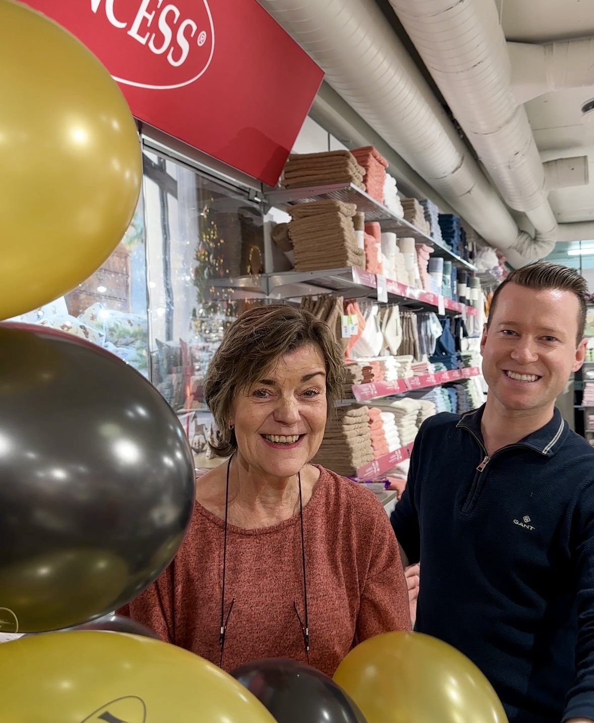 Princess 15 år på Lillestrøm Torv. Marit og butikksjef, Stian, smiler bredt bak disken, omringet av jubileumsballonger